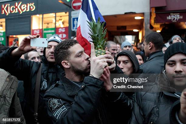 Fans of the French comic Dieudonne M'Bala M'Bala gather close to a theater in Paris, as one of them waves the French national flag and hold a...