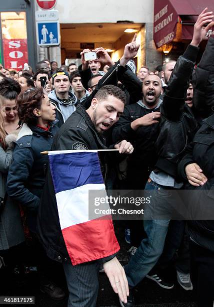 Fans of the French comic Dieudonne M'Bala M'Bala gather close to a theater in Paris, as one of them waves the French national flag and hold a...