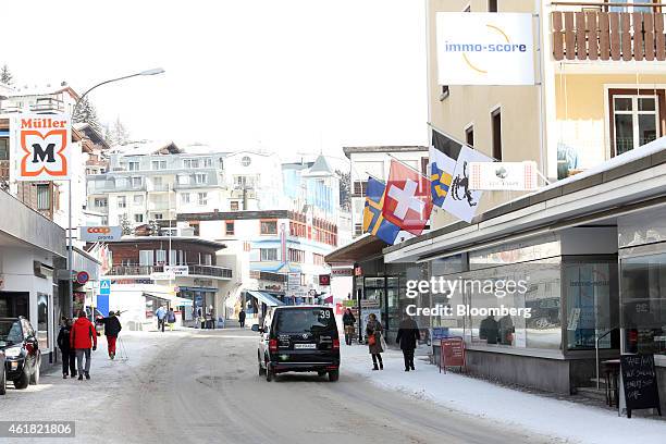 An official World Economic Forum shuttle bus passes pedestrians as they walk along the snow-covered Promenade high street ahead of the World Economic...