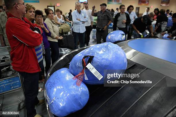 Luggage and goods, wrapped in plastic to protect against tampering and theft, are stacked on the conveyor belt in the baggae claim area at Jose Marti...