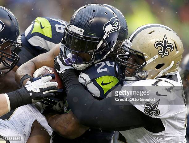 Running back Marshawn Lynch of the Seattle Seahawks runs the ball as he is hit by nose tackle Brodrick Bunkley of the New Orleans Saints in the...