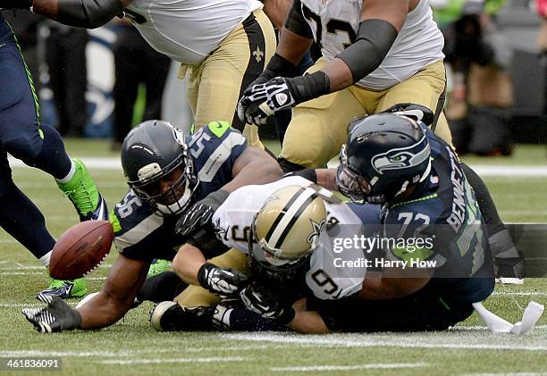 Quarterback Drew Brees of the New Orleans Saints is sacked by defensive end Cliff Avril and defensive end Michael Bennett of the Seattle Seahawks in...