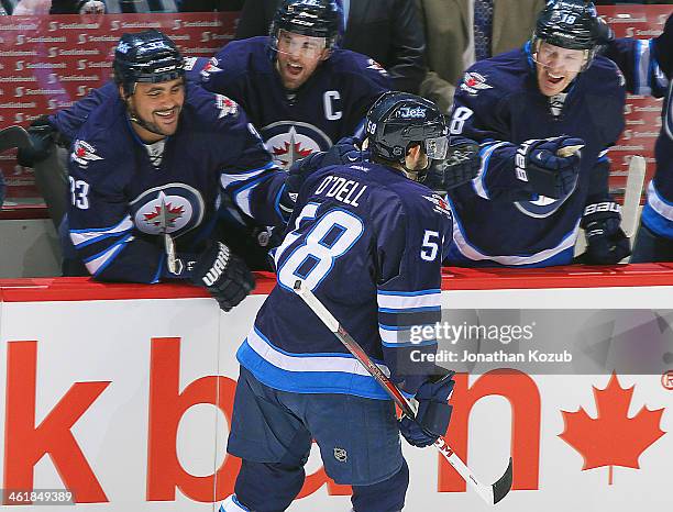 Eric O'Dell of the Winnipeg Jets is congratulated by teammates Dustin Byfuglien, Andrew Ladd and Bryan Little at the bench after scoring his first...
