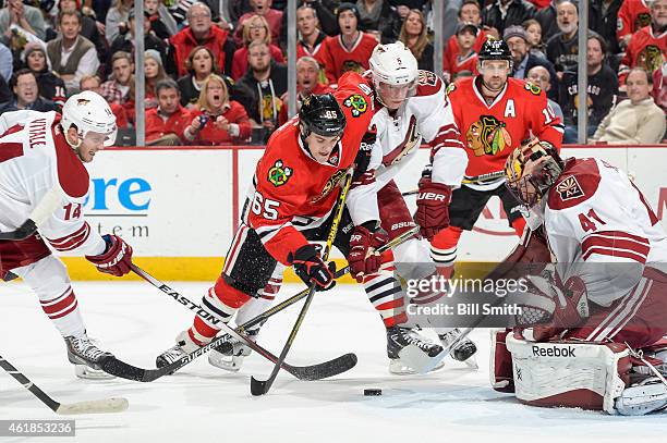 Andrew Shaw of the Chicago Blackhawks battles for the puck against Joe Vitale and Connor Murphy of the Arizona Coyotes in front of goalie Mike Smith...