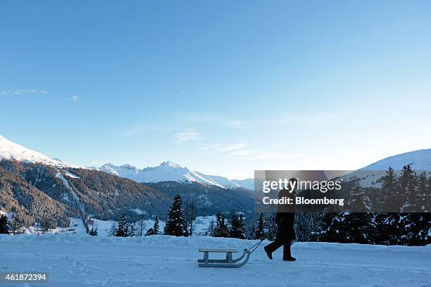 Man drags a toboggan through the snow on a mountainside ahead of the World Economic Forum in Davos, Switzerland, on Tuesday, Jan. 20, 2015. This week...