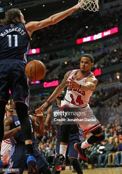 Augustin of the Chicago Bulls passes around Josh McRoberts of the Charlotte Bobcats at the United Center on January 11, 2014 in Chicago, Illinois....