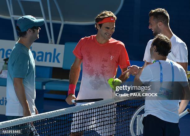 Switzerland's Roger Federer smiles as he speals with coaches during a practice session ahead of the 2014 Australian Open tennis tournament in...