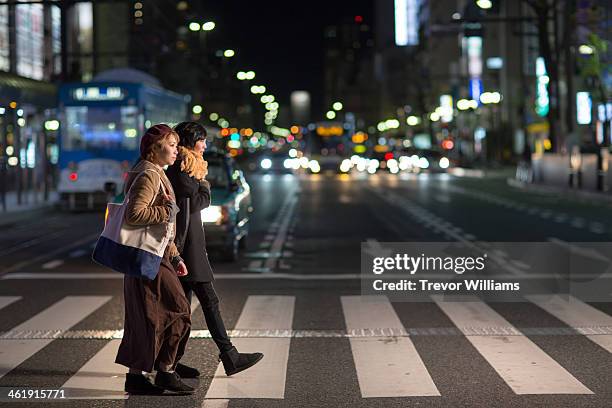 2 young women walking through city at night - crosswalk stock-fotos und bilder