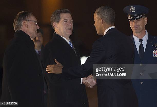 President Barack Obama shakes hands with Kansas Governor Sam Brownback alongside Topeka Mayor Larry Wolgast upon arrival on Air Force One at Forbes...