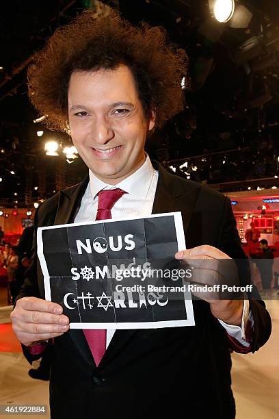 Magician Eric Antoine hangs a "Nous sommes Charlie" poster during the 'Vivement Dimanche' French TV Show at Pavillon Gabriel on January 21, 2015 in...