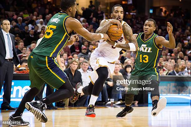 Smith of the Cleveland Cavaliers drives through Derrick Favors and Elijah Millsap of the Utah Jazz during the second half at Quicken Loans Arena on...