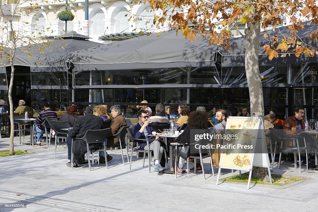 People sit in a cafe on Syntagma Square in the centre of...