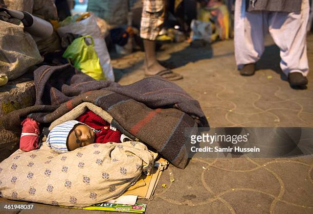 Young child sleeps on the street on December 11, 2013 in Kolkata, India. Almost one third of the Kolkata population live in slums and a further...
