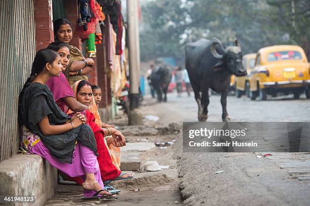 Group of women look on at a street scene in a slum on December 11, 2013 in Kolkata, India. Almost one third of the Kolkata population live in slums...