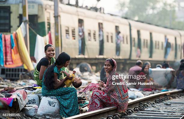 Women take care of a baby in a slum on the railway tracks as a commuter train goes past on December 12, 2013 in Kolkata, India. Almost one third of...