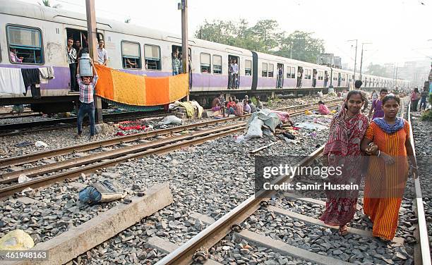 Women walk through a slum by the railway tracks as a commuter train goes past on December 12, 2013 in Kolkata, India. Almost one third of the Kolkata...