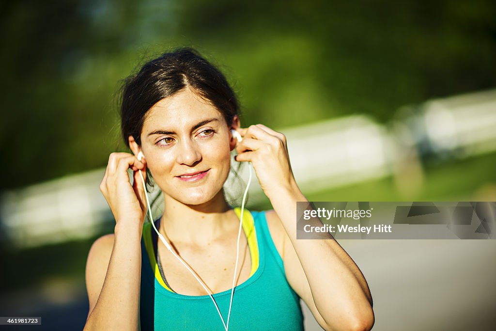 Woman jogger plugging in her ear plugs