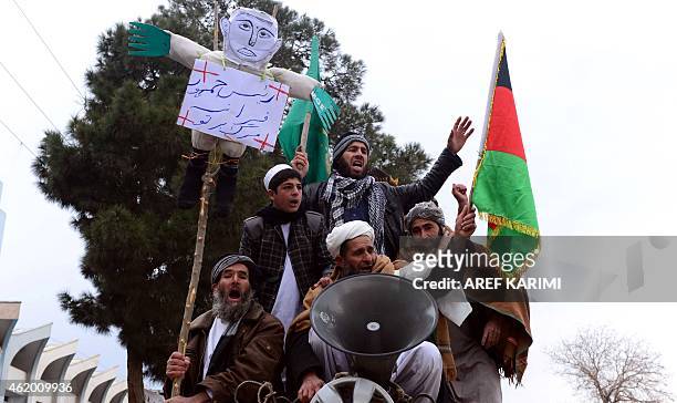 Afghan demonstrators chant slogans while holds up a effigy of the French President Francois Hollande during a protest against the printing of...