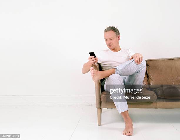 man with smartphone on sofa - sitting and using smartphone studio stockfoto's en -beelden