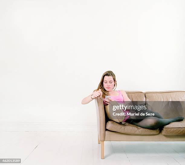 girl with smartphone on sofa - sitting and using smartphone studio stock pictures, royalty-free photos & images