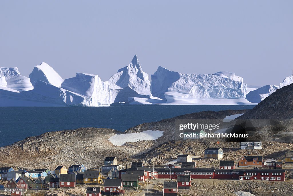 Icebergs behind houses on hill