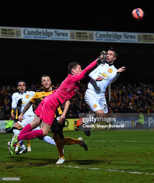 Chris Dunn of Cambridge United makes contact with Robin van Persie of Manchester United as he punches the ball clear during the FA Cup Fourth Round...