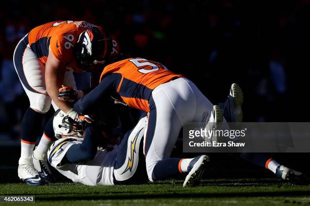 Philip Rivers of the San Diego Chargers gets sacked by Jeremy Mincey and Mitch Unrein of the Denver Broncos in the first quarter during the AFC...