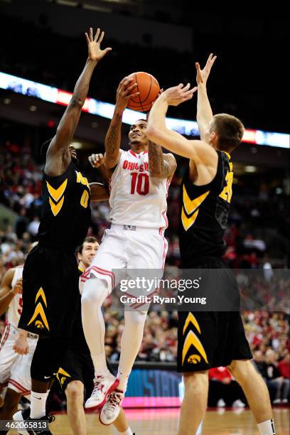 LaQuinton Ross of the Ohio State Buckeyes goes up for a layup while being defended by Jarrod Uthoff of the Iowa Hawkeyes and Gabriel Olaseni of the...
