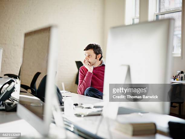 Businessman at desk in office studying computer