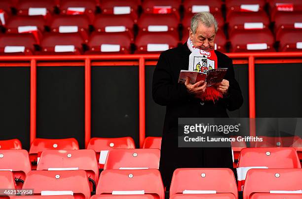Bristol City fan reads the match day programme inside the stadium before the FA Cup Fourth Round match between Bristol City and West Ham United at...