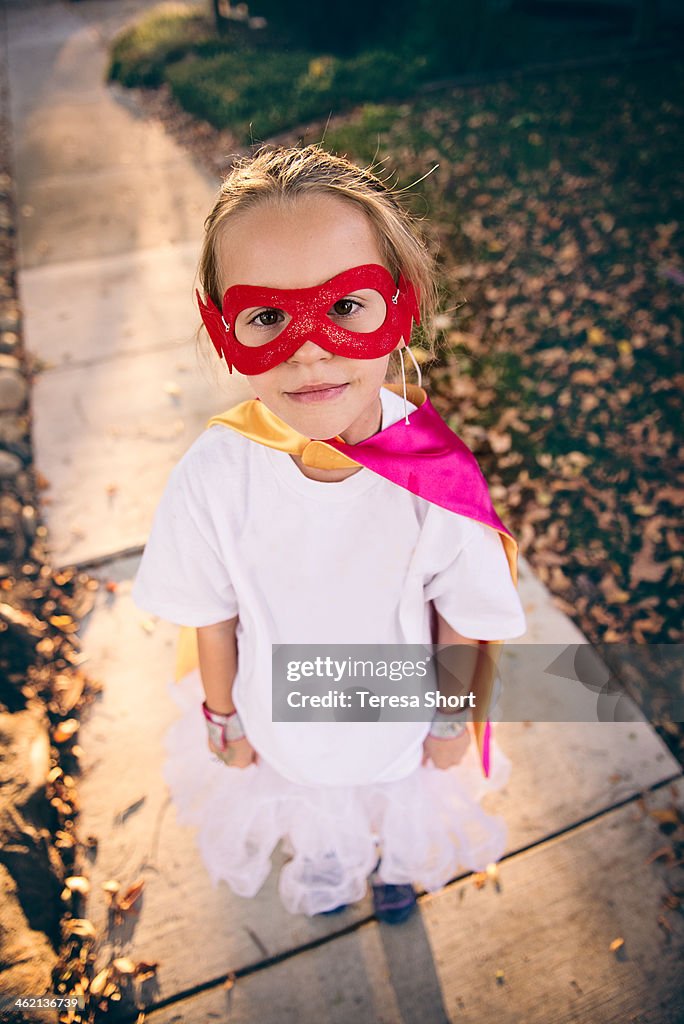Girl wearing superhero mask and cape
