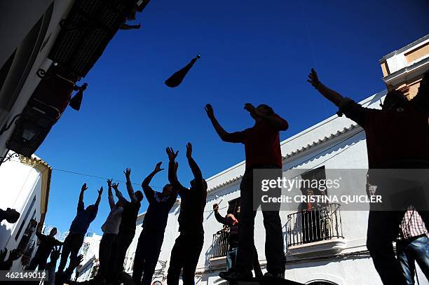 People from the southern Spanish village of Trigueros throw hams from their windows while the crowd try to grab them during the celebration of San...