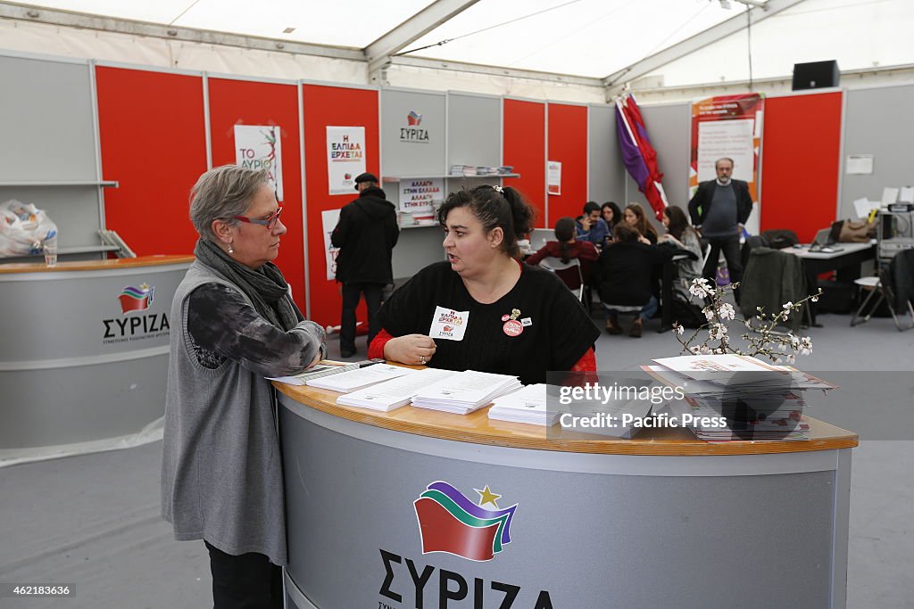 A SYRIZA campaigner talks to a woman in the election booth.