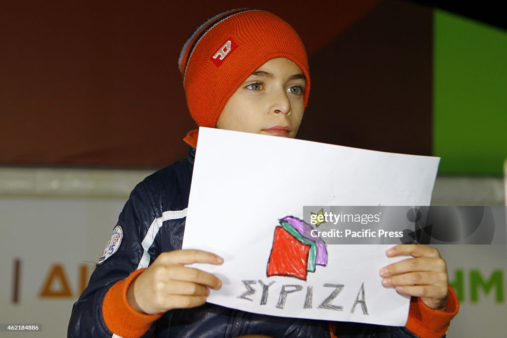 A boy holds a poster with a self drawn SYRIZA flag.