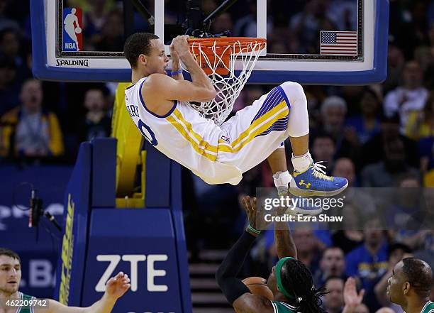 Stephen Curry of the Golden State Warriors hangs on the rim after dunking the ball on Gerald Wallace of the Boston Celtics at ORACLE Arena on January...