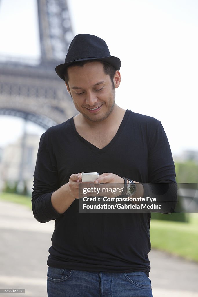 Man texting on cell phone outdoors by Eiffel Tower