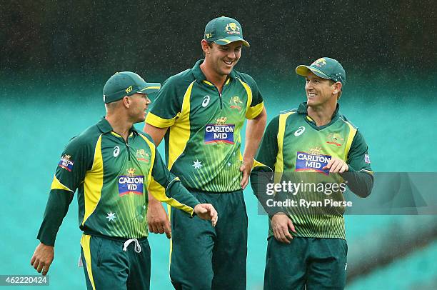 David Warner, Josh Hazlewood and George Bailey of Australia leave the ground as rain stops play during the One Day International match between...