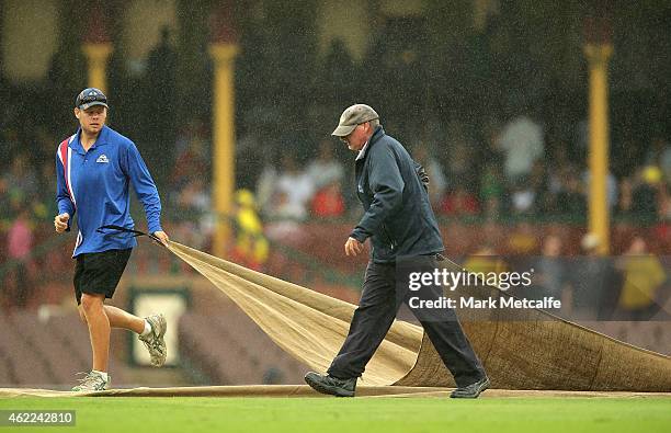 Groundsmen cover the pitch as rain falls during the One Day International match between Australia and India at Sydney Cricket Ground on January 26,...