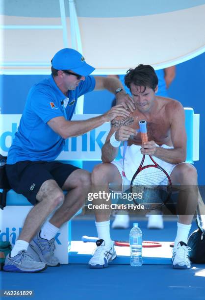 Tommy Haas of Germany is treated by a trainer in his first round match against Guillermo Garcia-Lopez of Spain during day one of the 2014 Australian...