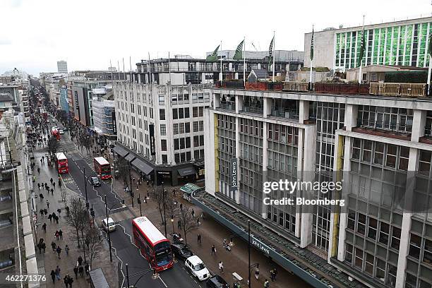 Red double deck buses, London taxi cabs and pedestrians pass department stores operated by John Lewis Plc, House of Fraser and Debenhams Plc on...