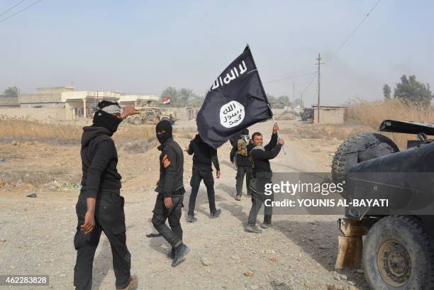 Iraqi government forces celebrate while holding an Islamis Sate group flag after they claimed they have gained complete control of the Diyala...
