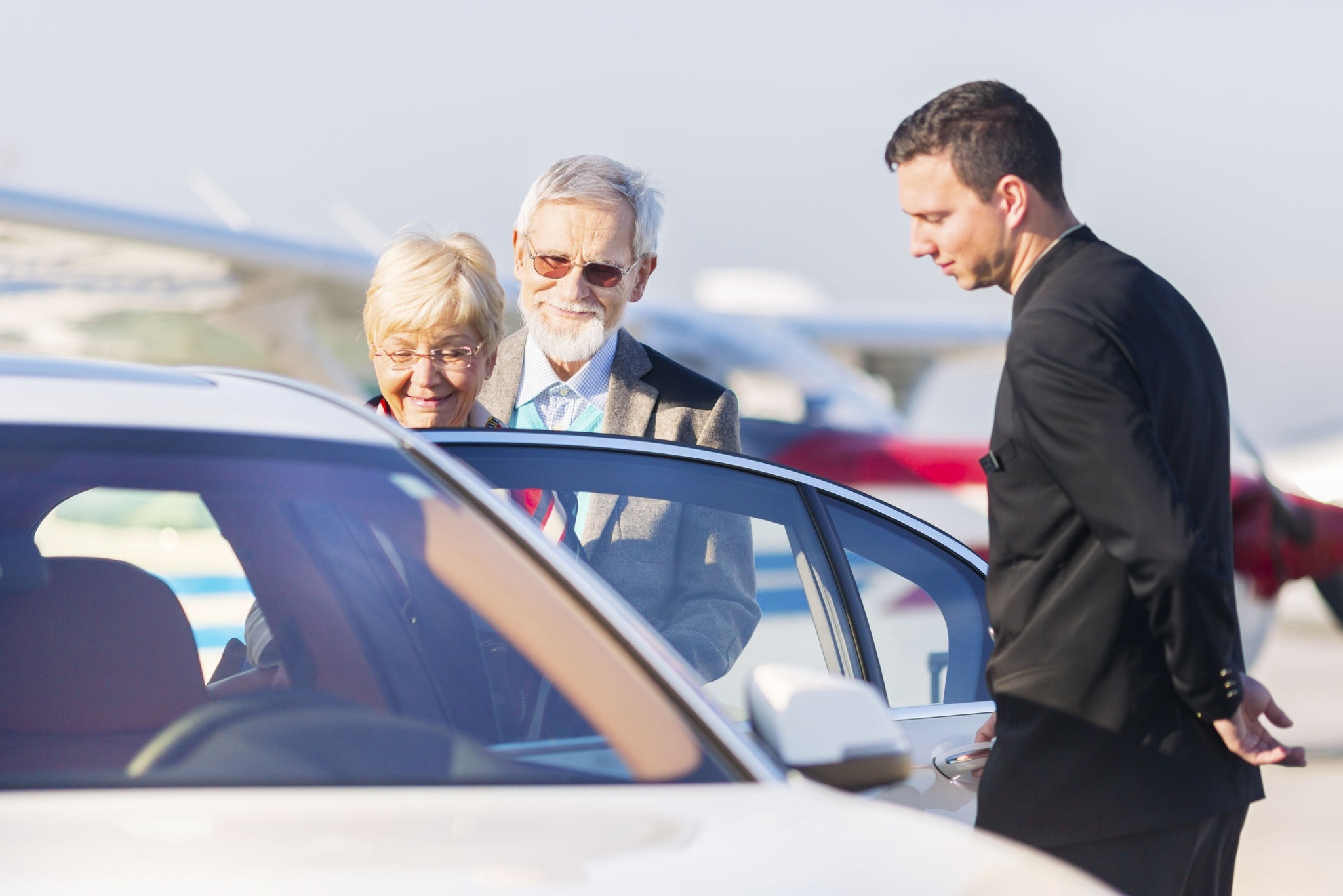 Senior couple leaving airport in chauffeured car Senior couple leaving airport in chauffeured car
