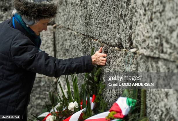 Holocaust survivor pays tribute to fallen comrades putting her hand on the "death wall" execution spot in the former Auschwitz concentration camp in...