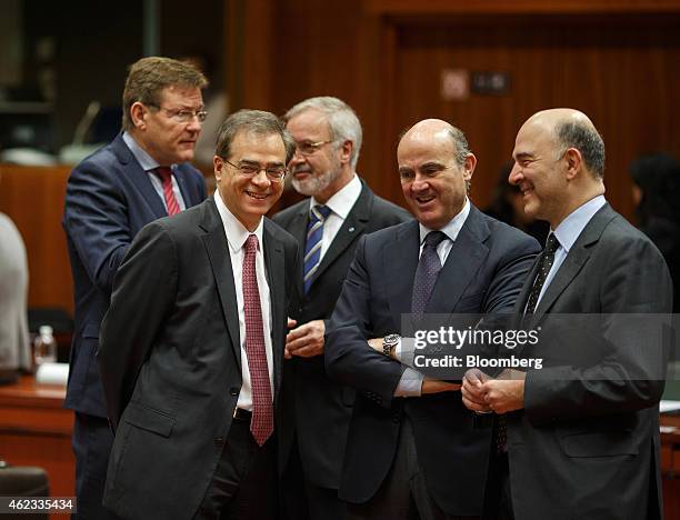 Gikas Hardouvelis, Greece's finance minister, left, reacts as he talks with Pierre Moscovici, European Union's economic commissioner, right, and Luis...