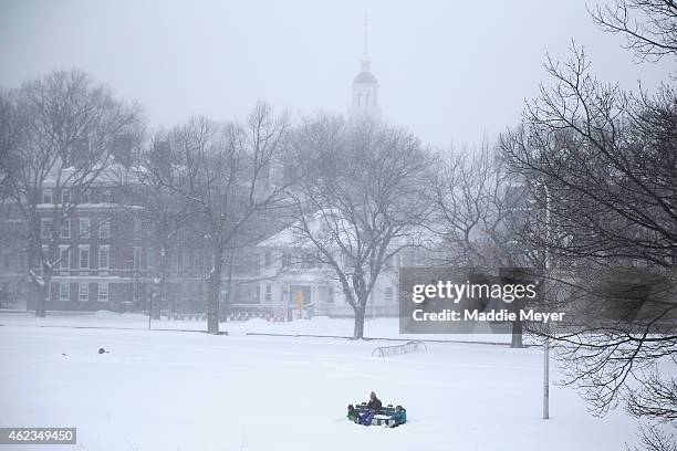 People sit together on the bank of the Charles River on January 27, 2015 in Cambridge, Massachusetts. Boston, and much of the Northeast, is being hit...