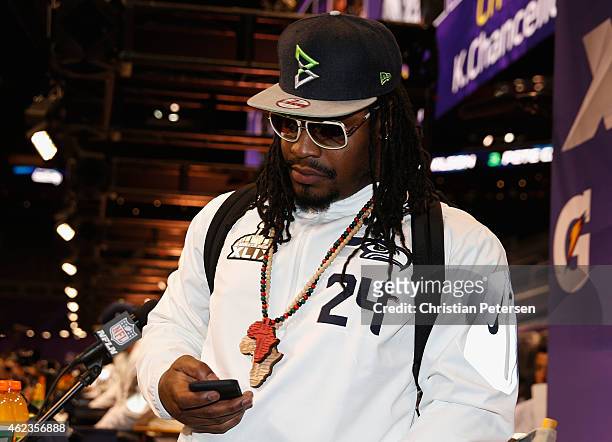 Marshawn Lynch of the Seattle Seahawks looks at his phone at Super Bowl XLIX Media Day Fueled by Gatorade inside U.S. Airways Center on January 27,...