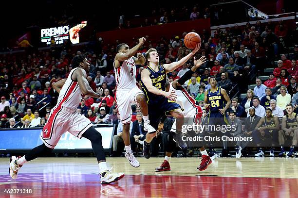 Spike Albrecht of the Michigan Wolverines drives for a shot attempt against Myles Mack of the Rutgers Scarlet Knights during their Big Ten conference...
