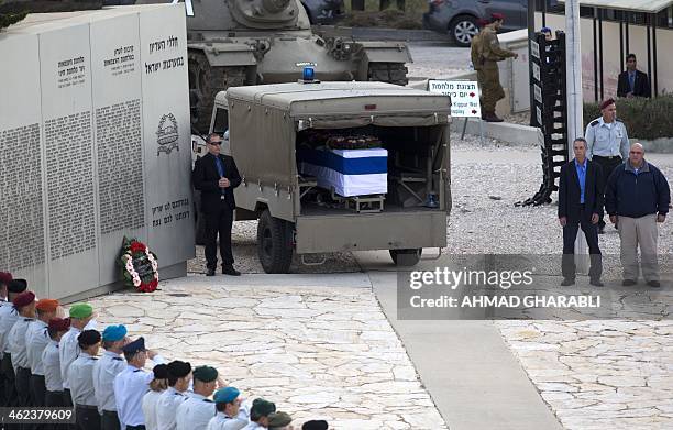 Gilad and Omri , the sons of the former Israeli prime minister Ariel Sharon, stand near his flag draped coffin sitting inside a vehicle, as it stops...