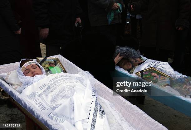 Mourners stand by the death bodies of Nikolay and Lyubov Bobilev, their daughter Marina Kashina, and their 3-years old grandson Vyacheslav during...