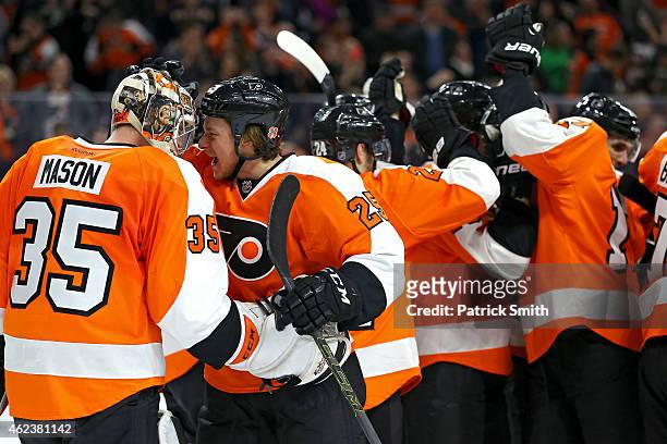 Goalie Steve Mason of the Philadelphia Flyers celebrates with teammate Ryan White after defeating the Arizona Coyotes at Wells Fargo Center on...